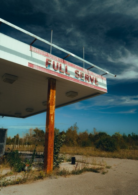 A vintage Full Serve gas station canopy beneath a blue sky.