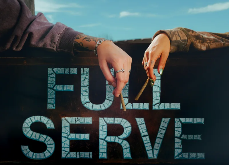 Two hands resting above a weathered Full Serve sign beneath a blue sky.