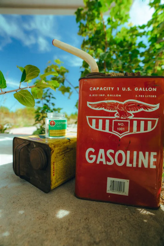 A red vintage Gasoline tin beside a Coterie jar and yellow packaging in the sunshine.