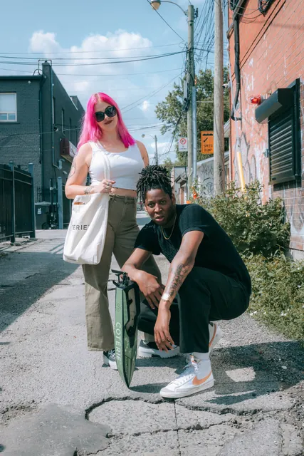 Two people posing outside a colourful storefront during a Coterie campaign shoot.
